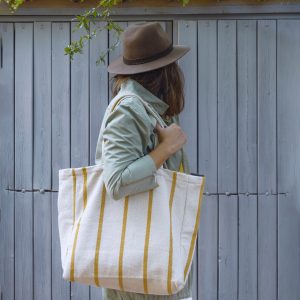 Mujer con sombrero paseando con bolsa algodón maxi Verdonce rayas mostaza